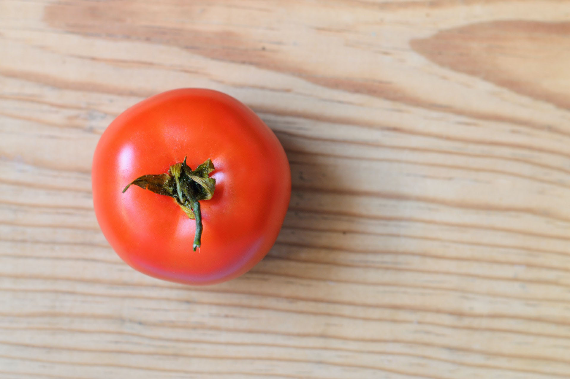 Image of tomato on wooden surface.